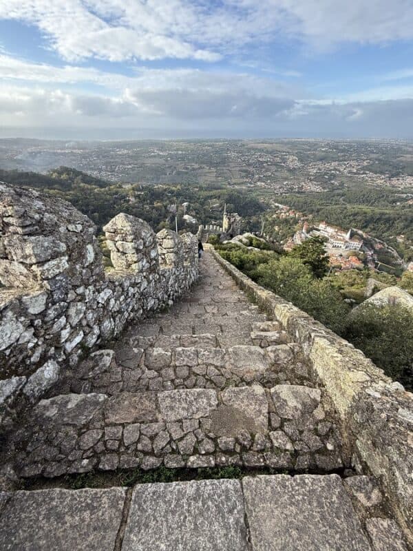 Stone steps run along the Moorish Castle walls, overlooking the forests and rooftops of Sintra below.