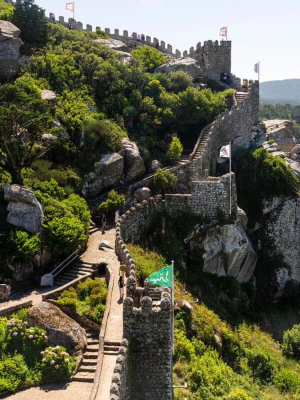 series of winding tall stone steps of moorish castle leading to mountaintop with castle flags waving