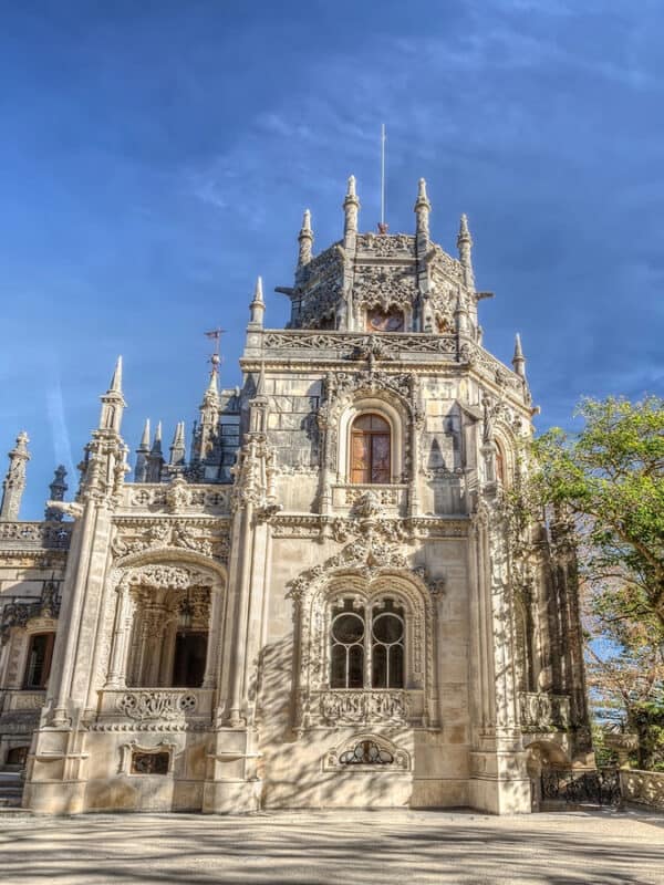 Quinta da Regaleira palace with ornate stone carvings and towers under a blue sky
