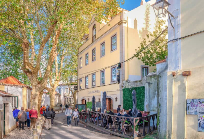 Casa do Vinho Sintra Guest House on Rua Consiglieri Pedroso, surrounded by trees, historic buildings and a busy outdoor café terrace.