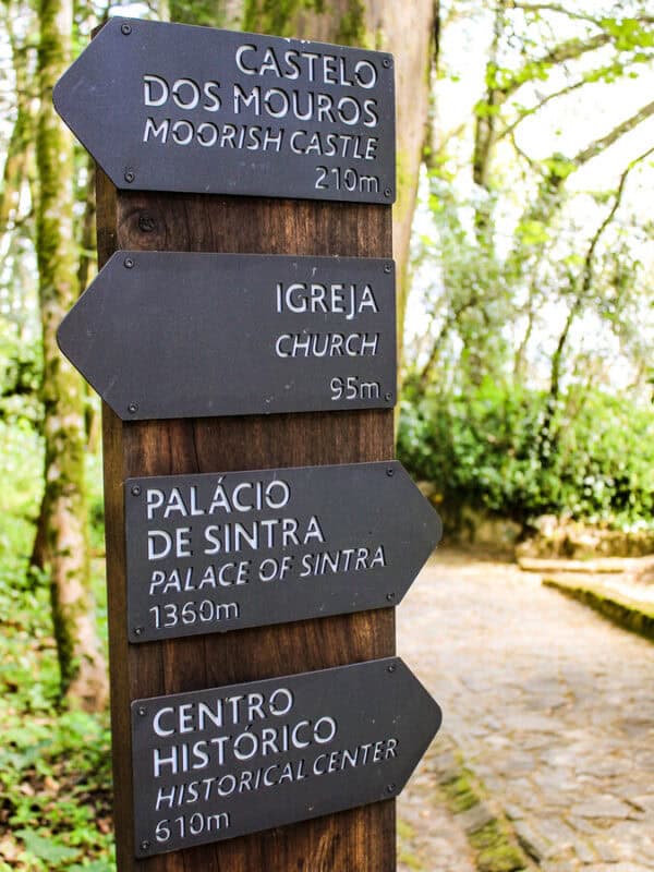 A trail sign points towards Moorish Castle, the church, Pena Palace and Sintra Historic Centre through the forest.