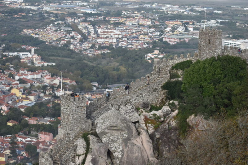 Moorish Castle walls and rocky outcrops overlook the red roofed neighbourhoods and green hills of Sintra.