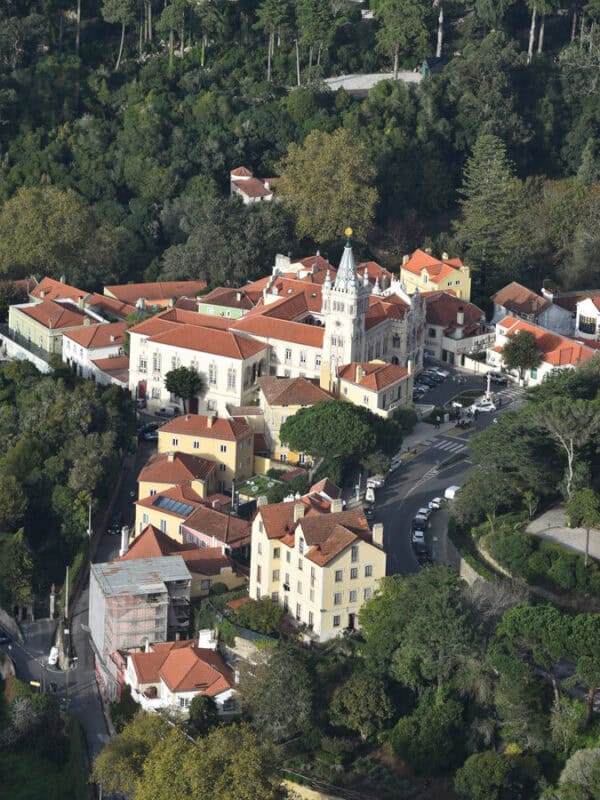 The white buildings and red roofs of Sintra Historic Centre are visible from the slopes of Moorish Castle.