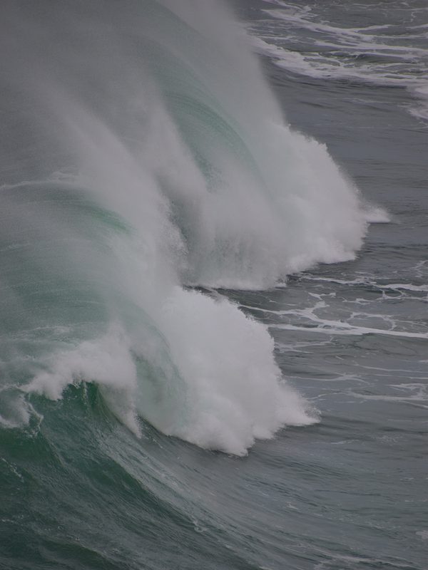 A 14 foot high wave crashing at Praia do Norte in Nazaré, Portugal, with powerful whitewater rising above the ocean