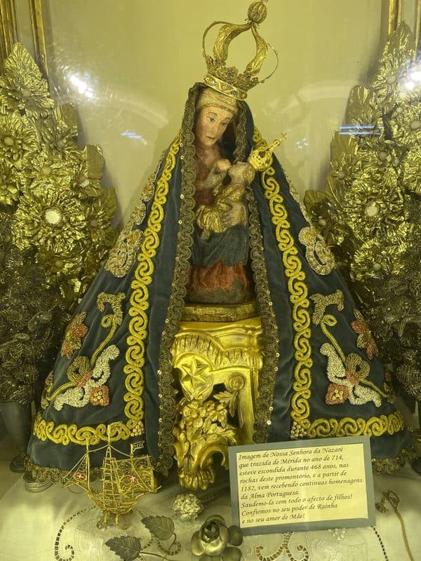 Statue of Our Lady of Nazaré breastfeeding baby Jesus inside the sanctuary, surrounded by ornate church decoration