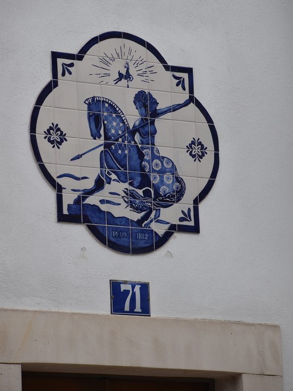 Blue and white azulejo tile at Door 71 in Sítio, depicting the Virgin Mary saving a man on horseback chasing a deer