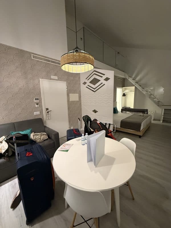 Large room at Hotel Magic in Nazaré with a bed area, lounge, upper loft and stairs, with suitcases and strollers inside
