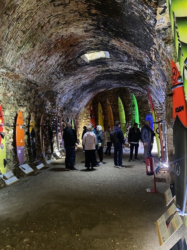 Surfing board museum inside the Forte de São Miguel Arcanjo in Nazaré, displayed beneath a stone vaulted roof