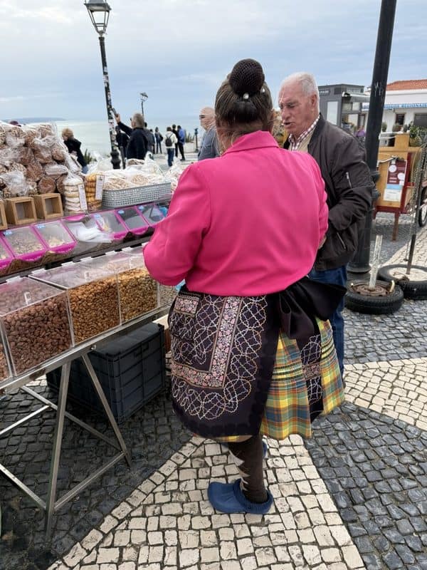 Sitio market stall with lady wearing seven layered skirt selling dried nuts and local snacks beside the waterfront