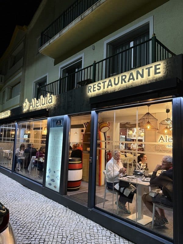 Aleluia Restaurante in Nazare, Portugal, with diners inside and traditional Portuguese pavement, with text on it that says Aleluia Restaurante